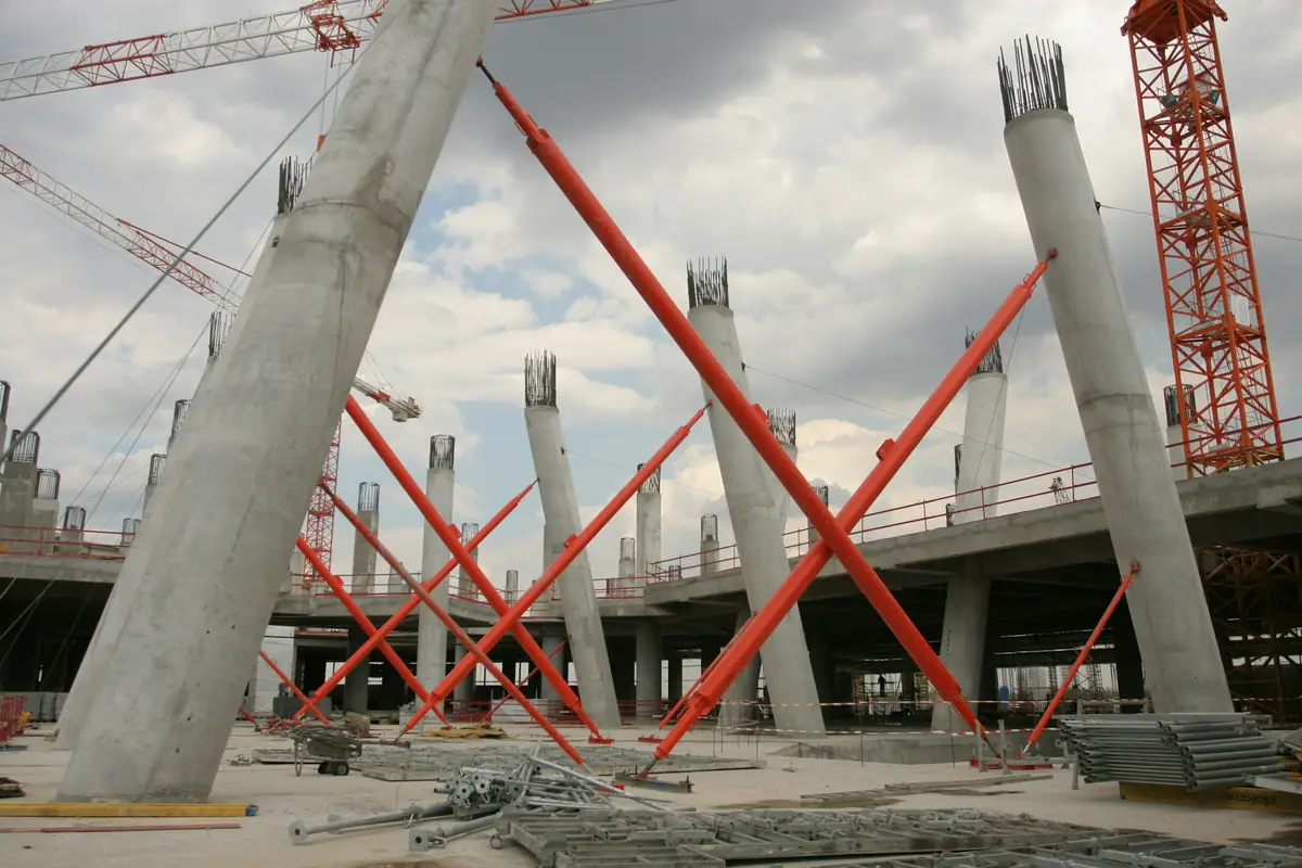 Schräge Stahlbetonstützen mit roten Abstützungen auf einer Großbaustelle